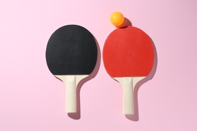 Photo of Ping pong rackets and ball on pink background, flat lay
