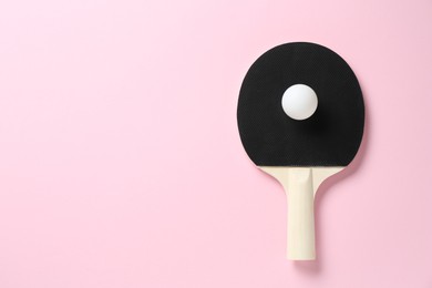 Photo of Ping pong racket and ball on pink background, top view. Space for text