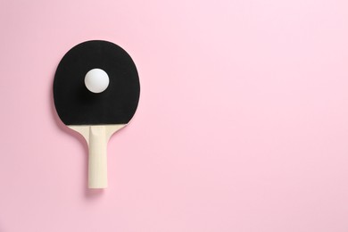 Photo of Ping pong racket and ball on pink background, top view. Space for text
