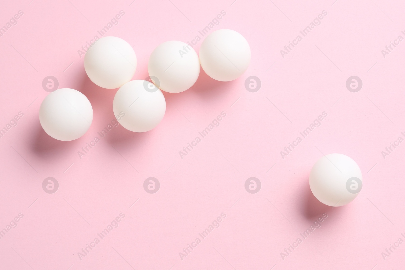 Many ping pong balls on pink background, flat lay Photo of Many ping pong balls on pink background, flat lay