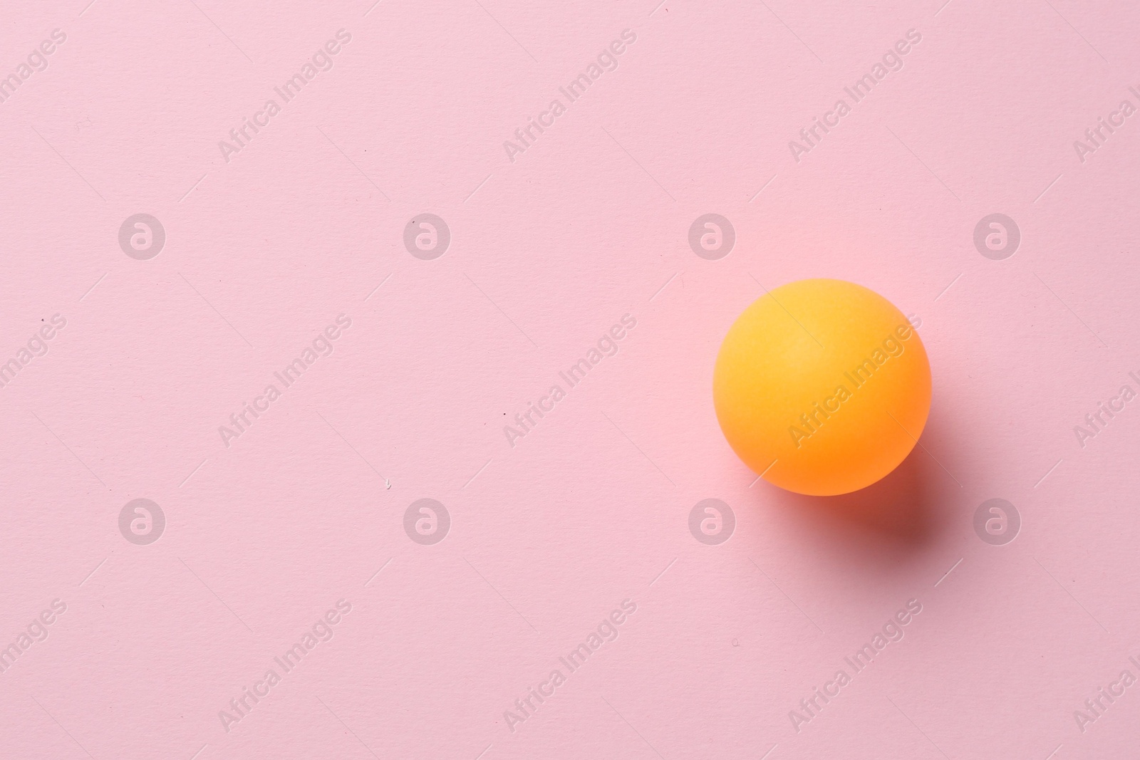 One ping pong ball on pink background, top view. Space for text Photo of One ping pong ball on pink background, top view. Space for text