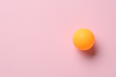Photo of One ping pong ball on pink background, top view. Space for text