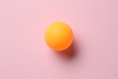 Photo of One ping pong ball on pink background, top view