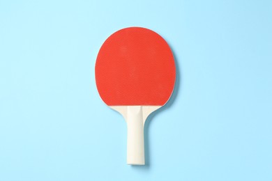 Photo of One ping pong racket on light blue background, top view