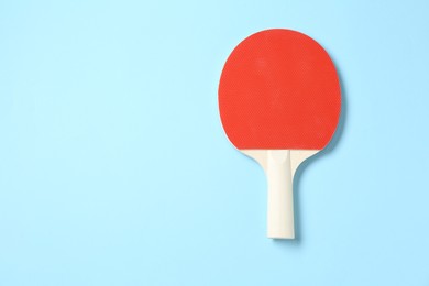 Photo of One ping pong racket on light blue background, top view. Space for text