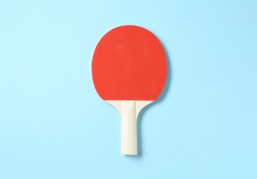 Photo of One ping pong racket on light blue background, top view