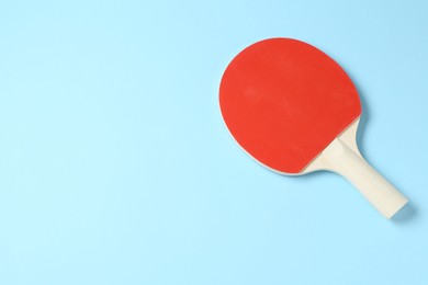 Photo of One ping pong racket on light blue background, top view. Space for text