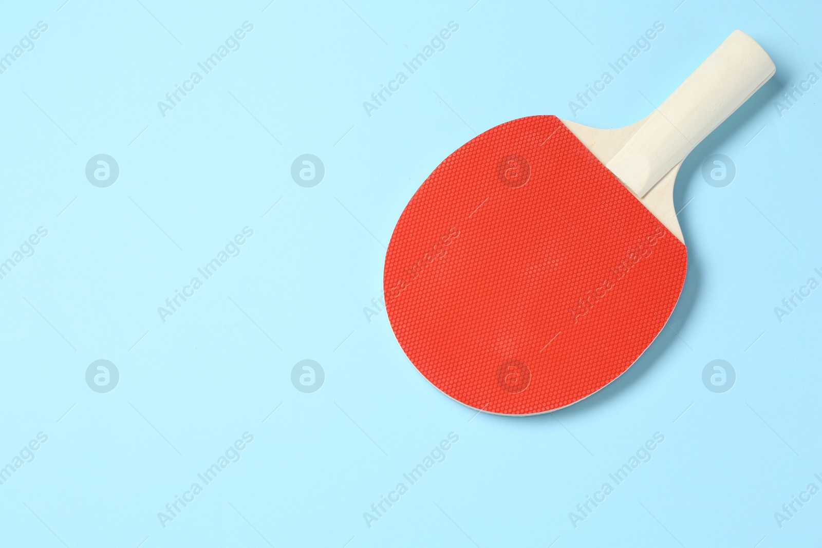 One ping pong racket on light blue background, top view. Space for text Photo of One ping pong racket on light blue background, top view. Space for text