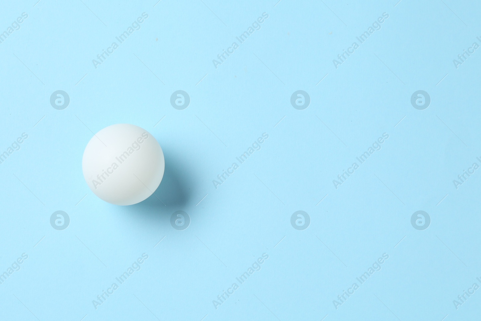 Ping pong ball on light blue background, top view. Space for text Photo of Ping pong ball on light blue background, top view. Space for text