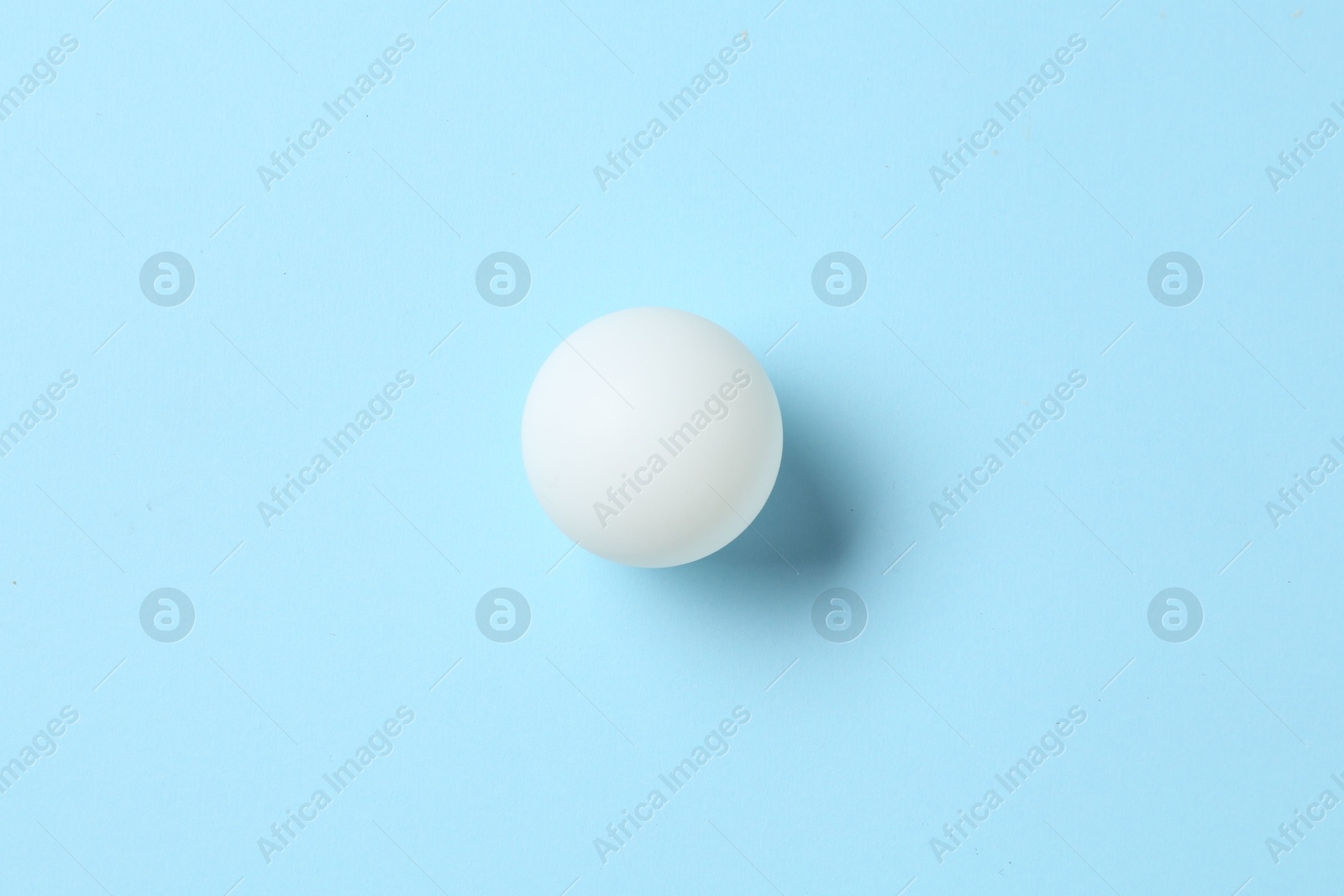 Ping pong ball on light blue background, top view Photo of Ping pong ball on light blue background, top view