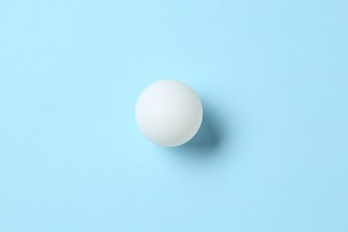 Photo of Ping pong ball on light blue background, top view