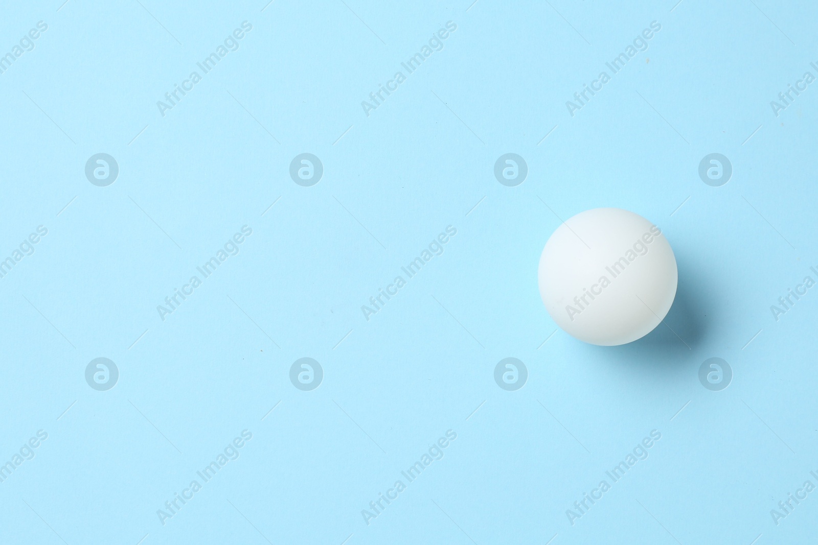 Ping pong ball on light blue background, top view. Space for text Photo of Ping pong ball on light blue background, top view. Space for text