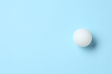 Photo of Ping pong ball on light blue background, top view. Space for text