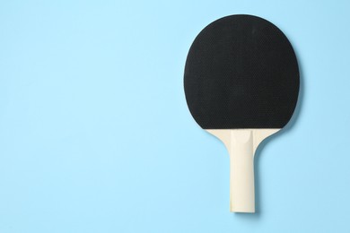 Photo of Ping pong racket on light blue background, top view. Space for text