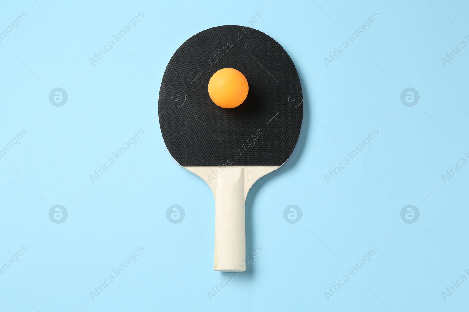 Ping pong racket and ball on light blue background, top view Photo of Ping pong racket and ball on light blue background, top view
