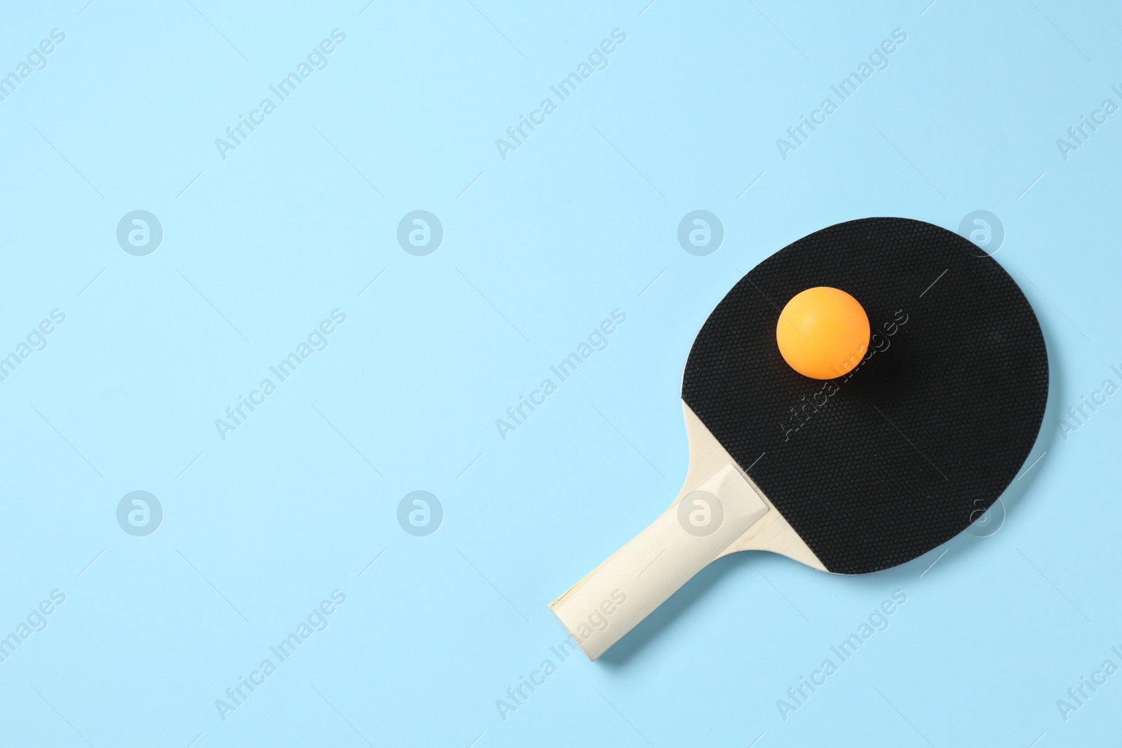 Ping pong racket and ball on light blue background, top view. Space for text Photo of Ping pong racket and ball on light blue background, top view. Space for text