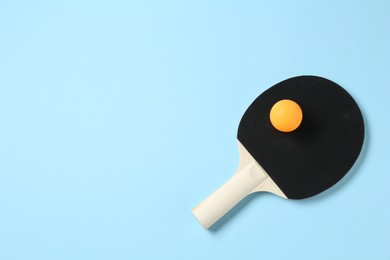 Photo of Ping pong racket and ball on light blue background, top view. Space for text