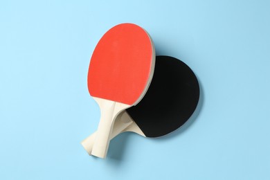 Photo of Ping pong rackets on light blue background, flat lay