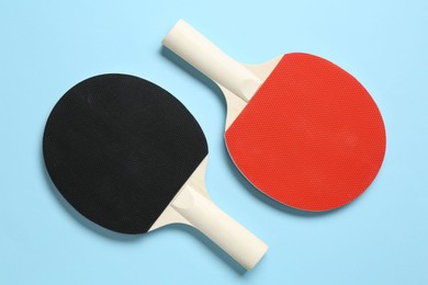 Photo of Ping pong rackets on light blue background, flat lay