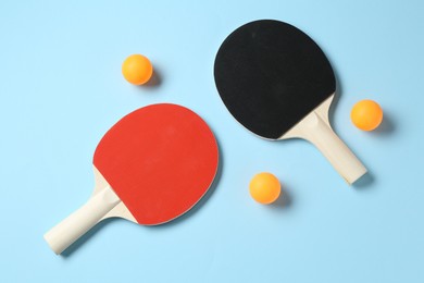 Photo of Ping pong rackets and balls on light blue background, flat lay