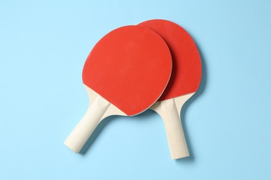Photo of Ping pong rackets on light blue background, flat lay