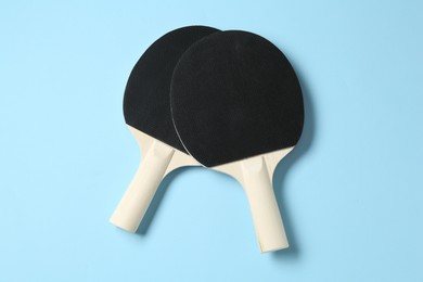 Photo of Ping pong rackets on light blue background, flat lay