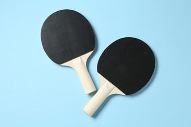 Photo of Ping pong rackets on light blue background, flat lay