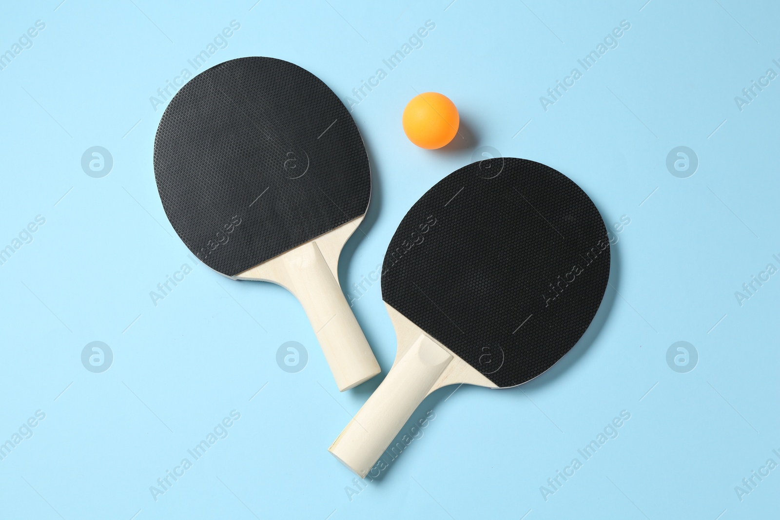 Ping pong rackets and ball on light blue background, flat lay Photo of Ping pong rackets and ball on light blue background, flat lay
