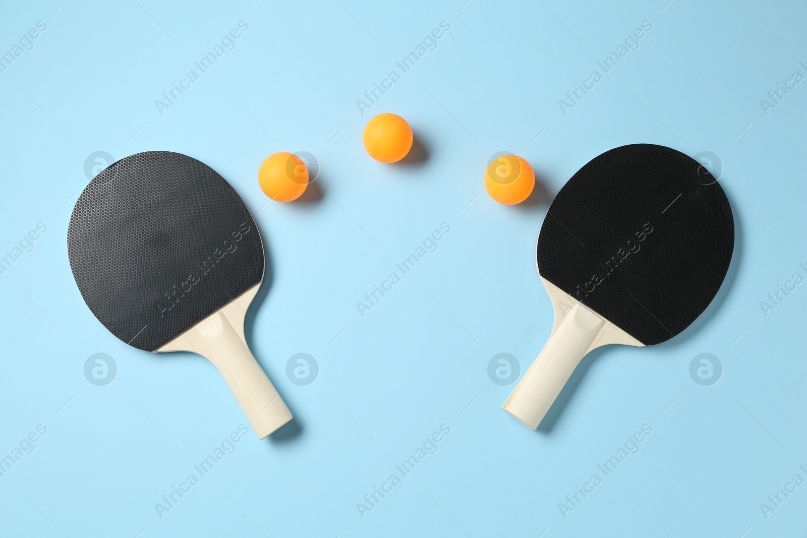 Ping pong rackets and balls on light blue background, flat lay Photo of Ping pong rackets and balls on light blue background, flat lay