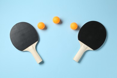 Photo of Ping pong rackets and balls on light blue background, flat lay