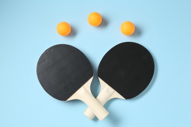 Photo of Ping pong rackets and balls on light blue background, flat lay