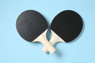 Photo of Ping pong rackets on light blue background, flat lay