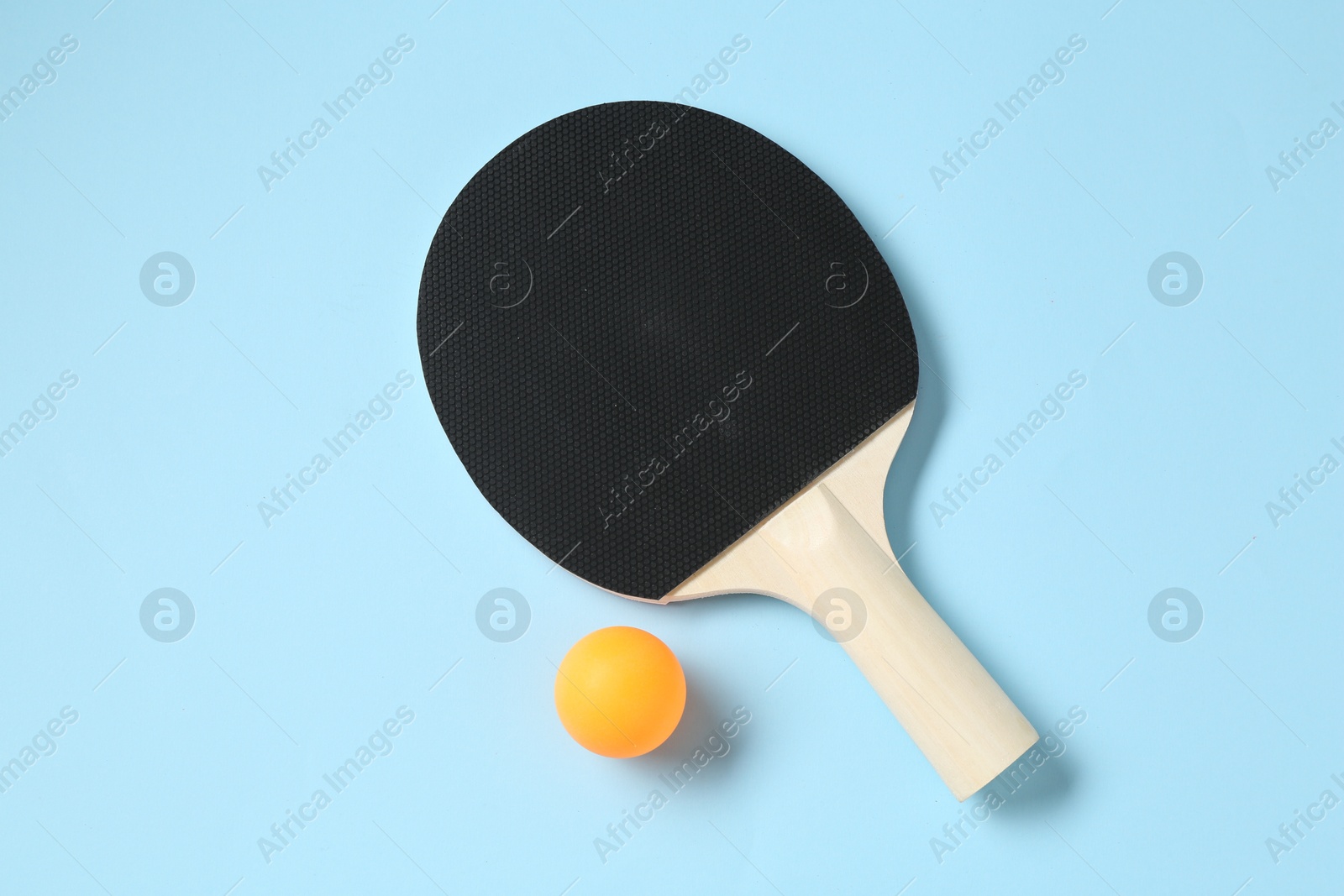 Ping pong racket and ball on light blue background, flat lay Photo of Ping pong racket and ball on light blue background, flat lay