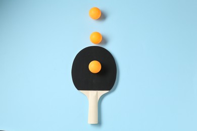 Photo of Ping pong racket and balls on light blue background, flat lay
