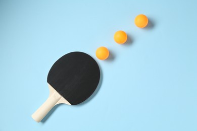 Photo of Ping pong racket and balls on light blue background, flat lay