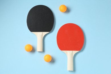 Photo of Ping pong rackets and balls on light blue background, flat lay