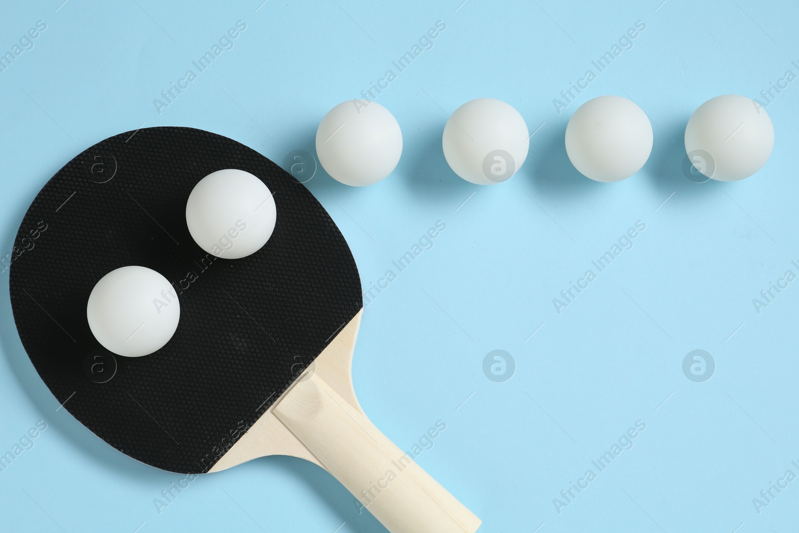 Ping pong racket and balls on light blue background, flat lay Photo of Ping pong racket and balls on light blue background, flat lay