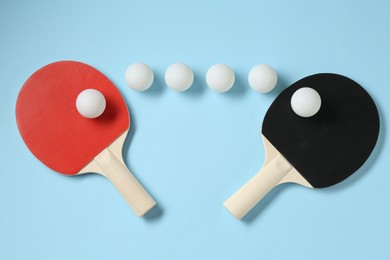 Photo of Ping pong rackets and balls on light blue background, flat lay
