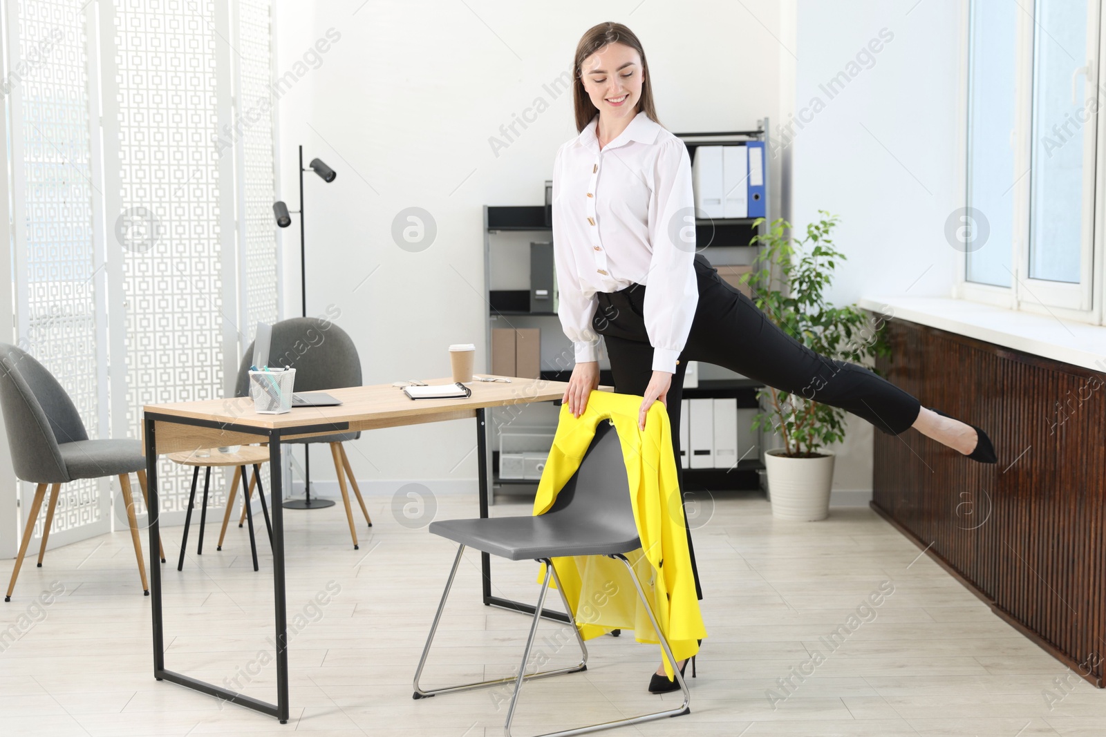 Beautiful woman exercising with chair in office Photo of Beautiful woman exercising with chair in office