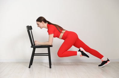 Photo of Beautiful woman exercising with chair at home