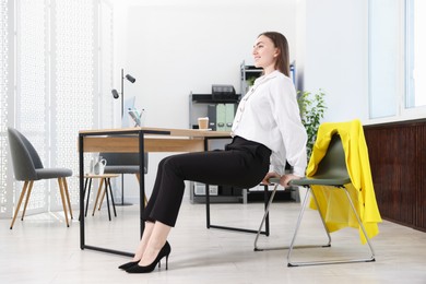 Photo of Beautiful woman exercising with chair in office