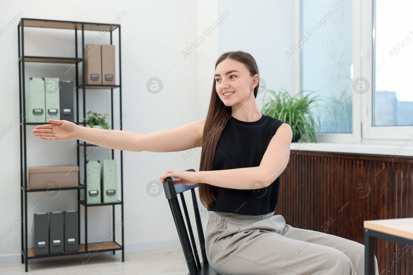 Beautiful woman stretching on chair in office Photo of Beautiful woman stretching on chair in office