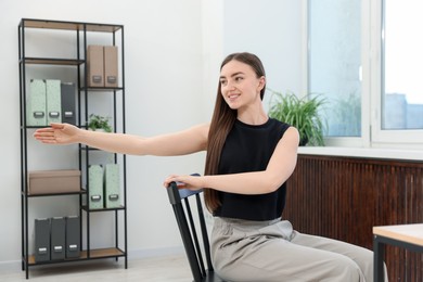 Photo of Beautiful woman stretching on chair in office