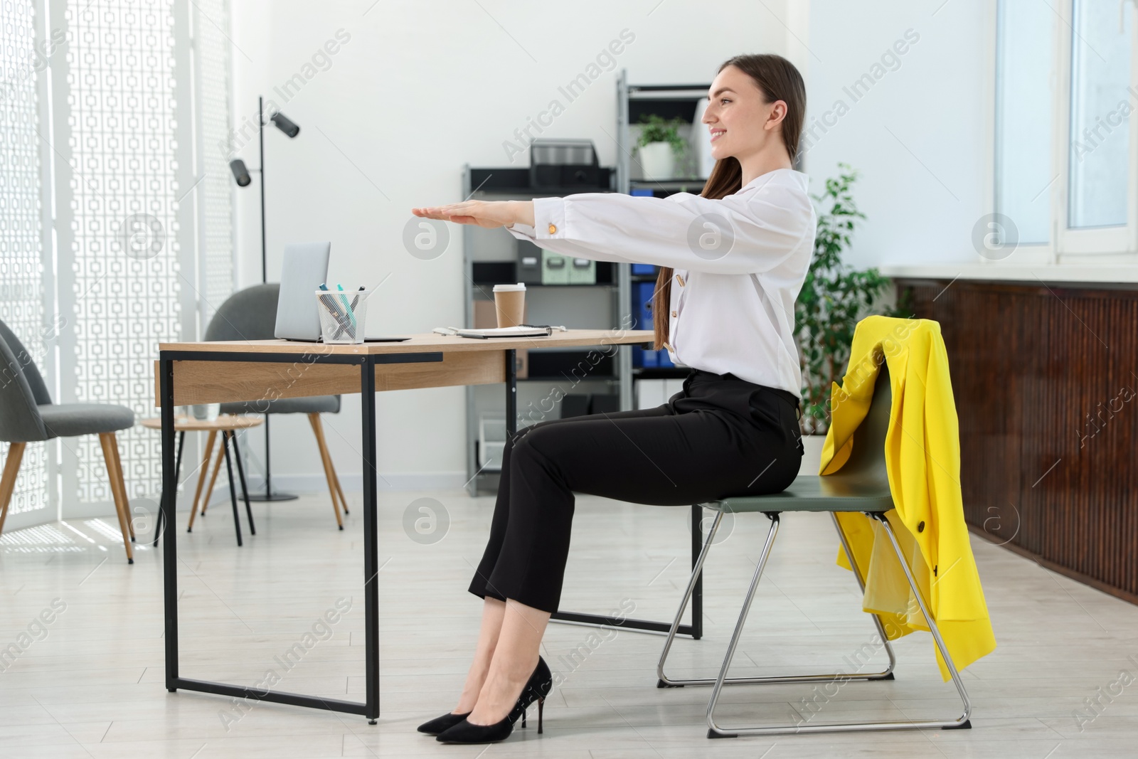 Beautiful woman stretching on chair in office Photo of Beautiful woman stretching on chair in office