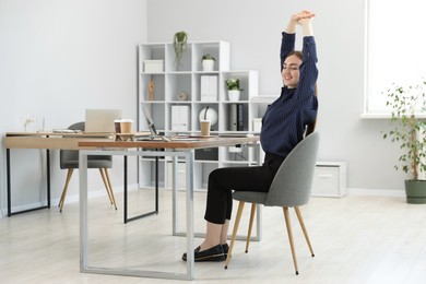 Photo of Beautiful woman stretching on chair in office