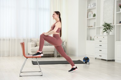 Photo of Beautiful woman exercising with chair at home