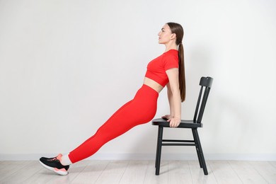 Photo of Beautiful woman exercising with chair at home