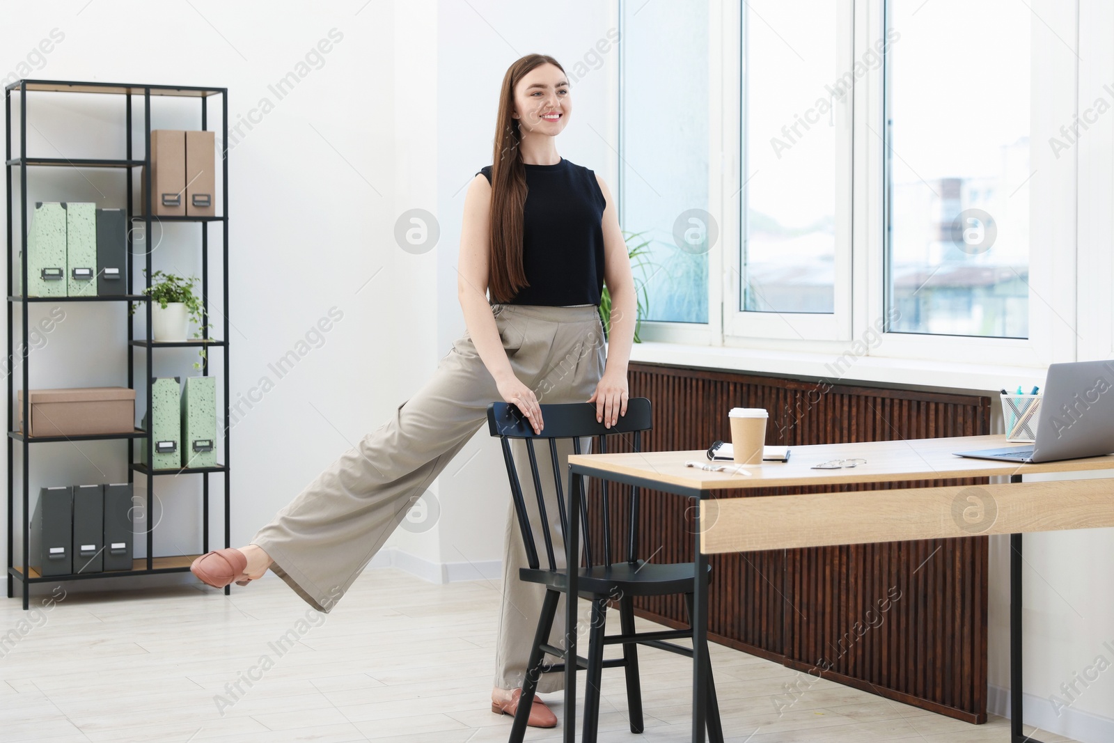Beautiful woman exercising with chair in office Photo of Beautiful woman exercising with chair in office