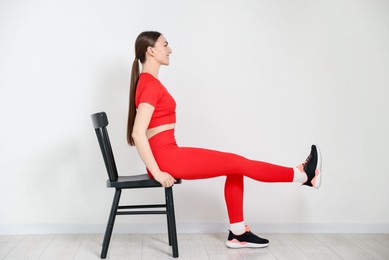 Photo of Beautiful woman exercising with chair at home