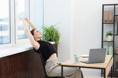 Photo of Beautiful woman stretching on chair in office